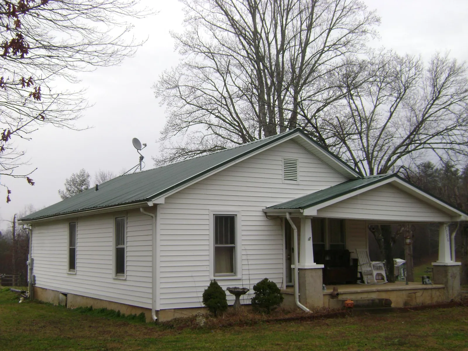 Green metal roof on a white bungalow with a side porch in Abbeville
